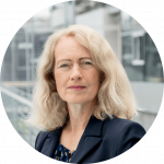 Ein Portrait von Diana Runge vor einem Gebäude mit Glaswänden.